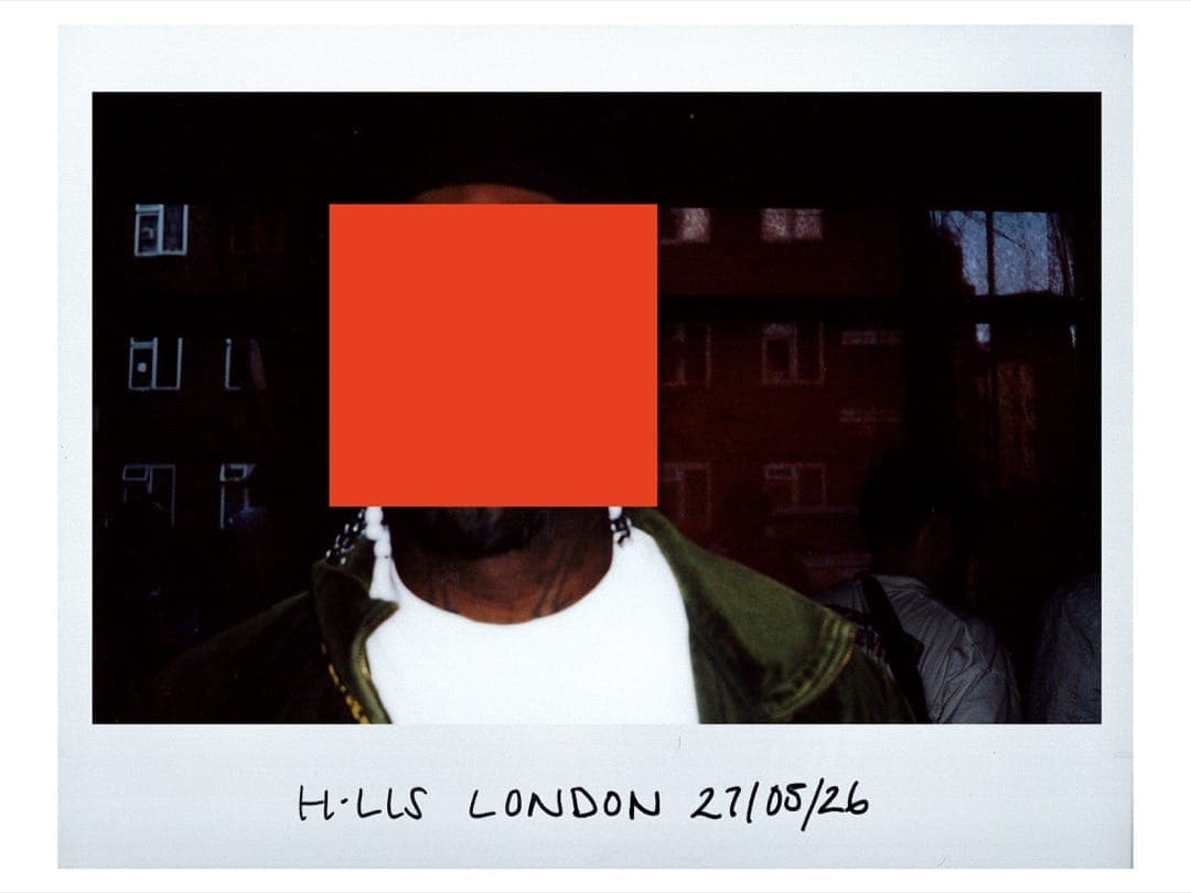 Kevin in a green jacket and white tee outside a brick estate, face hidden by an orange square