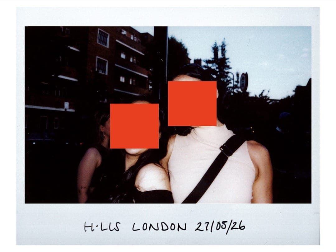 Lucy and Soar arm in arm on a London street at dusk, faces hidden by orange squares