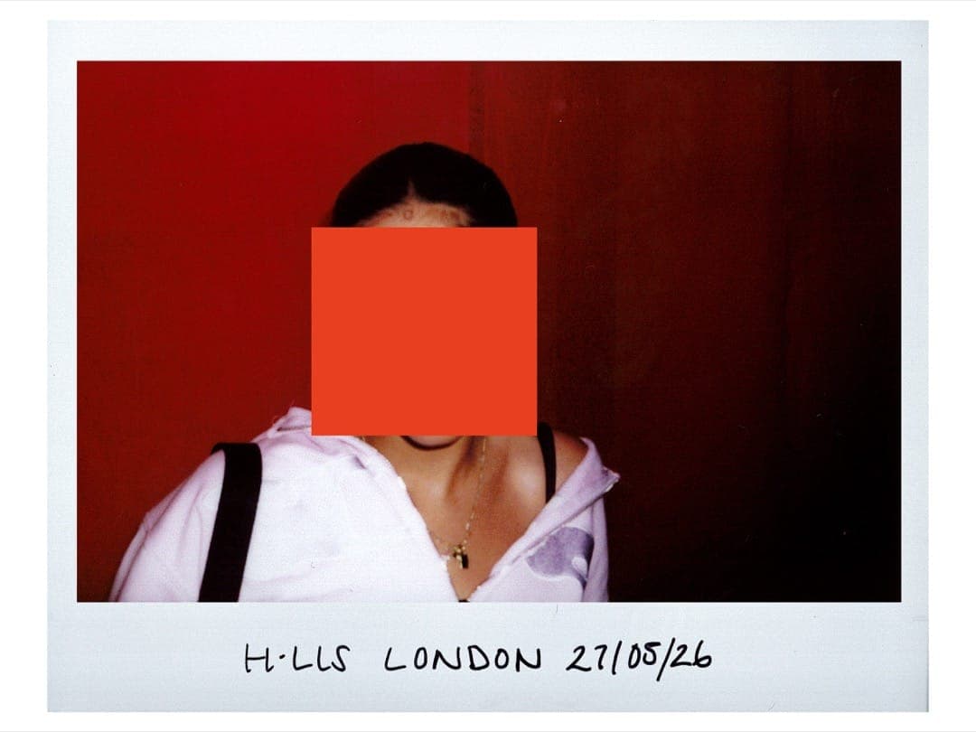 Maria in a white hoodie against a red backdrop, face hidden by an orange square