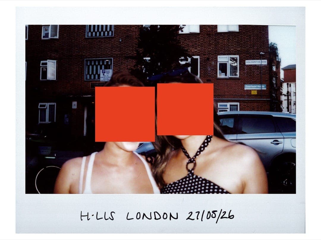 Two friends in summer tops outside a brick estate, faces covered by orange squares